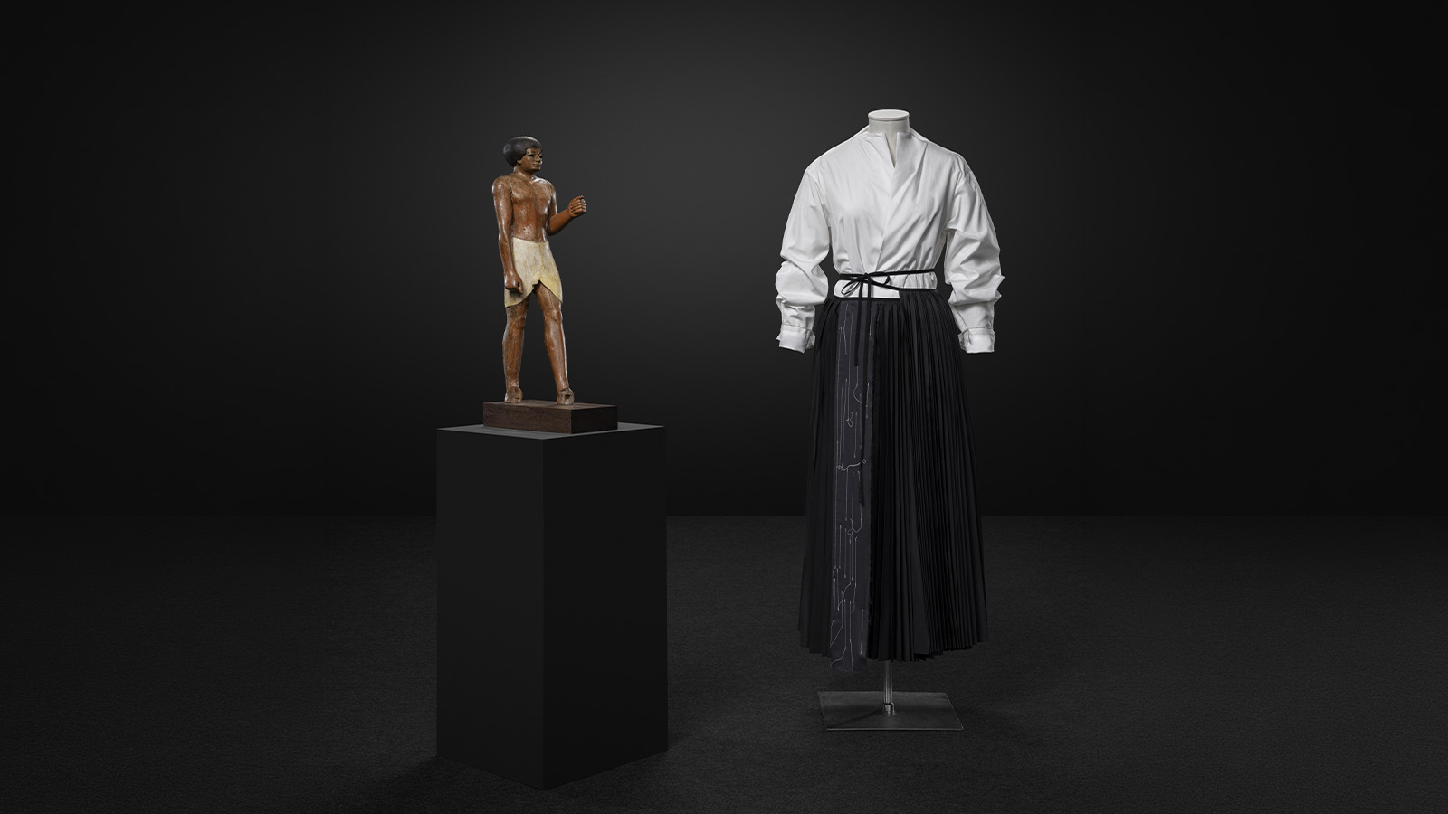 Estátua funerária Egito, região de Tebas, Império Médio, XI dinastia (c. 2000-1990 a. C.) Ébano policromo Museu Calouste Gulbenkian, inv. 142 Yohji Yamamoto Camisa e saia Prêt-à-porter outono/inverno 1999/2000 Popelina de algodão, tafetá de lã e nylon MUDE, Lisboa MUDE/Coleção Francisco Capelo/MUDE.M.0152 Fundação Calouste Gulbenkian. Foto: © Jon Cazenave