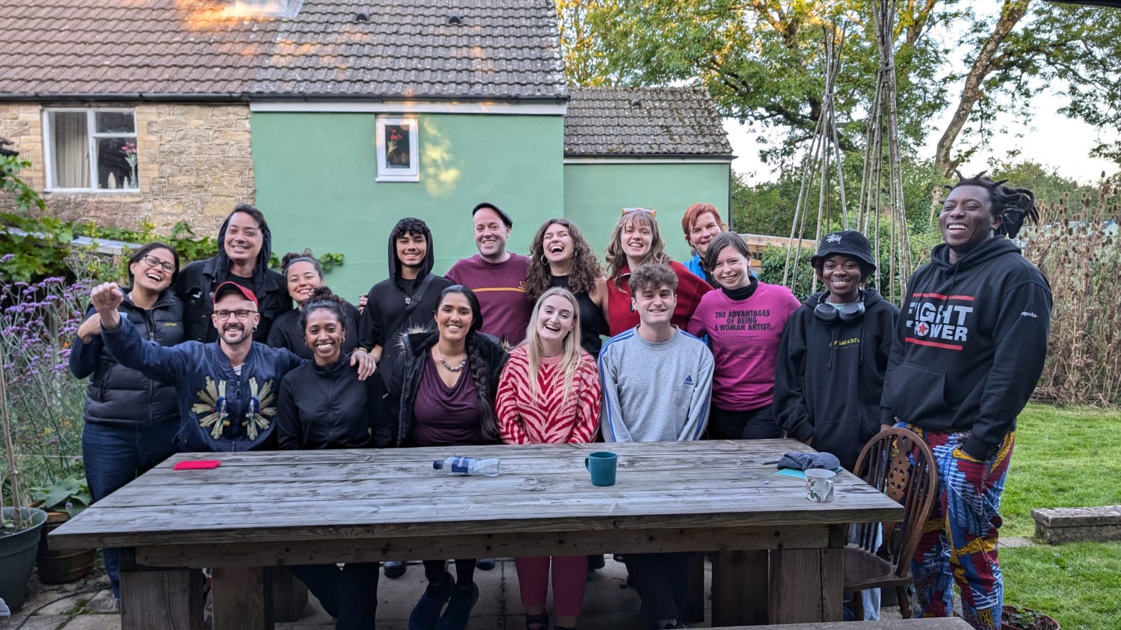 Young people sat at an outdoor bench smiling