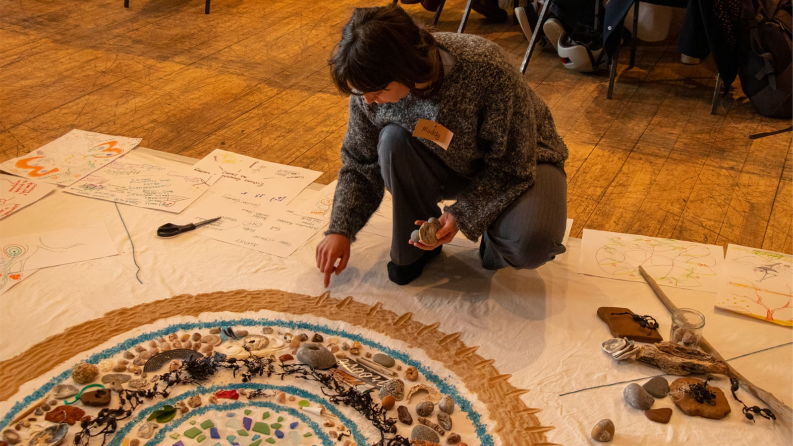 Woman sat on the floor making art from ocean materials