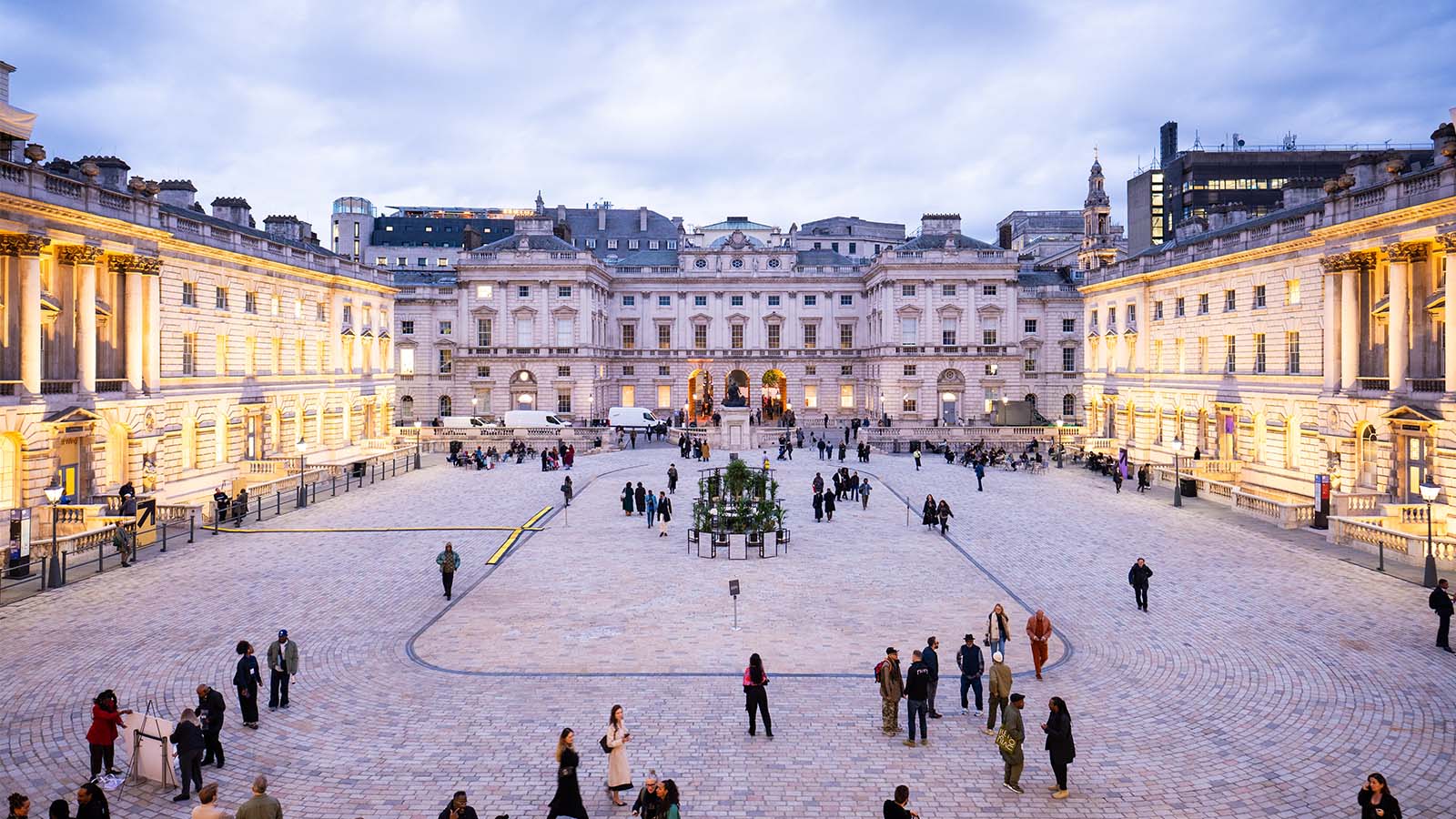 Courtyard lit up at night with people walking around