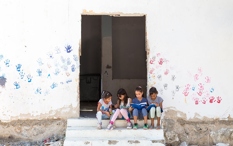 Lagadikia, Greece - August 25, 2016: Children sit on stairs in the refugee camp of Lagadikia, some 40km North of Thessaloniki, during the visit of UN high commissioner for refugees Filippo Grandi