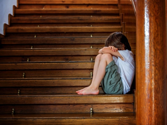 Sad child, sitting on a staircase in a big house, concept for bullying, depression stress or frustration