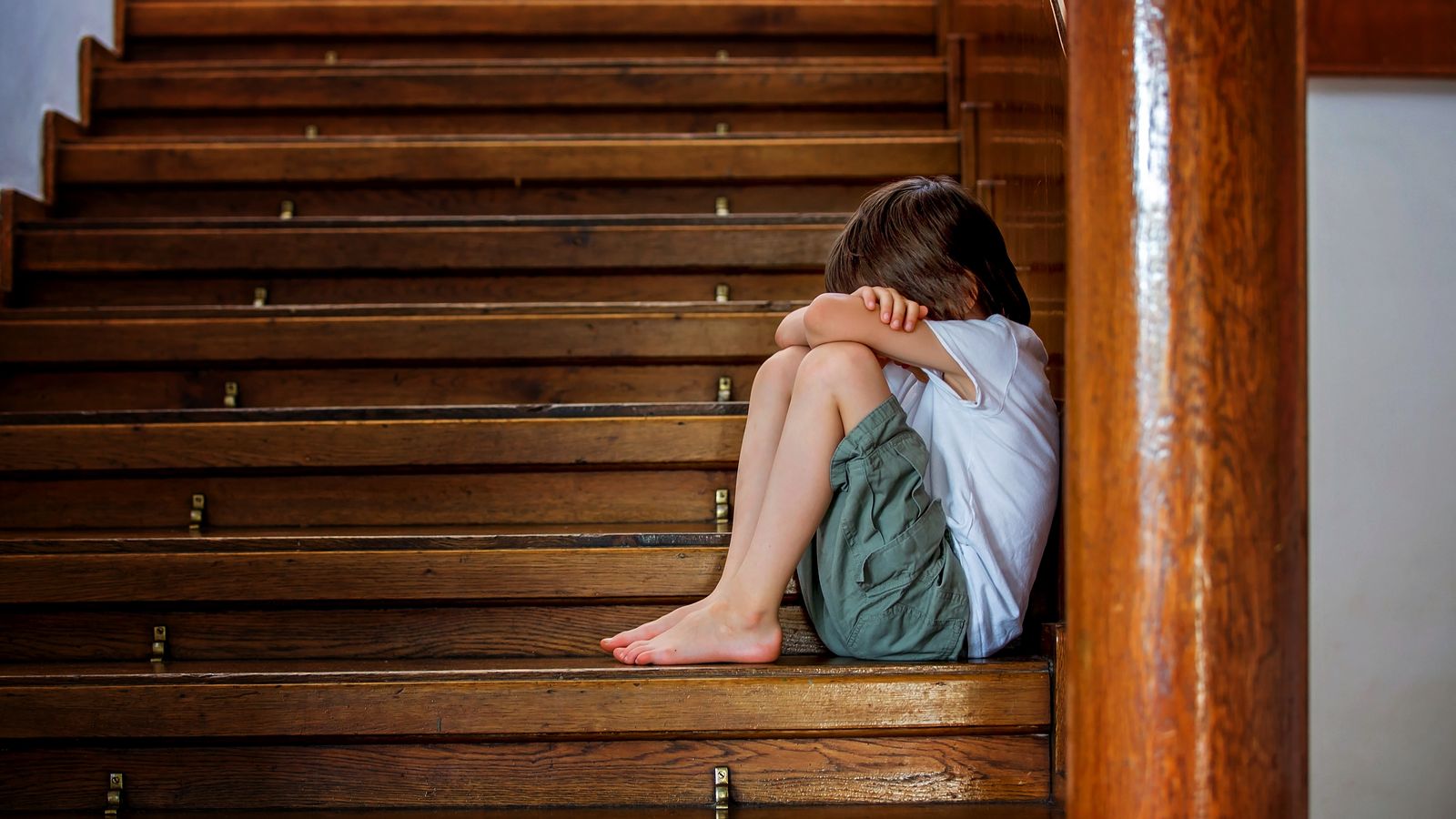 Sad child, sitting on a staircase in a big house, concept for bullying, depression stress or frustration