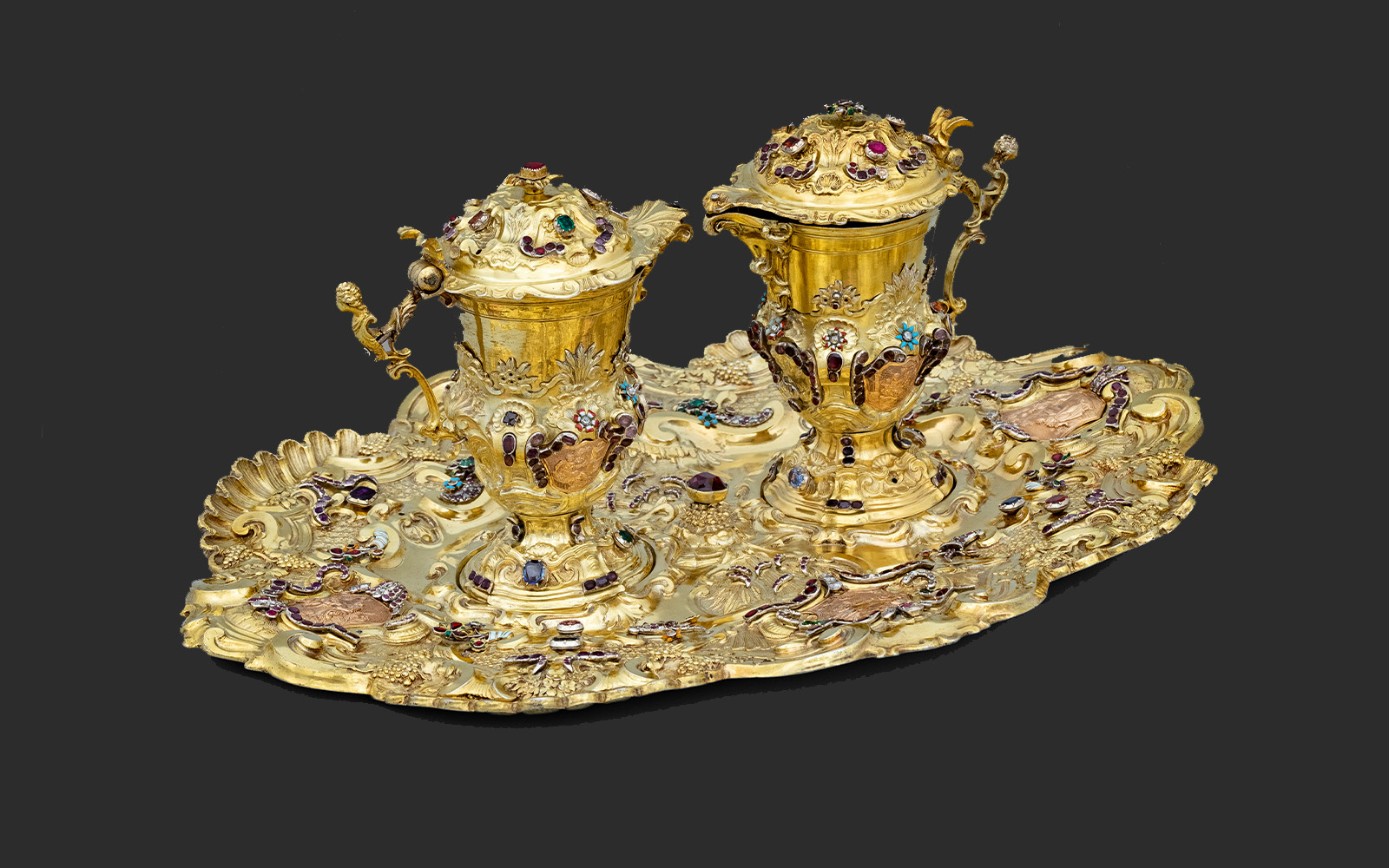 Silversmith ‘IK’, Altar cruets with tray. Vienna, 1740. Silver gilt, gold, enamel, rubies, sapphires, emeralds, almandine garnets, hessonite garnets, amethysts, diamonds and glasses. Terra Sancta Museum, Jerusalem, inv. CTS-OA-25463. Photo: © Guillaume Benoit/ CTS